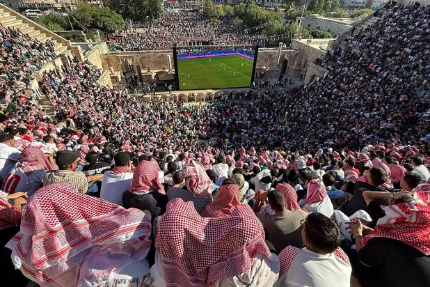 آلاف الأردنيين احتشدوا في المدرج الروماني التاريخي بعمّان لمتابعة الظهور الأول لمنتخبهم (أ.ف.ب)