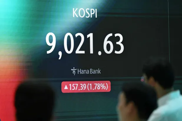 متداول عملات يقف أمام شاشة تظهر مؤشر الأسهم القياسي لكوريا الجنوبية الذي كسر 9000 نقطة في مقر بنك هانا في سيول (أ.ف.ب)