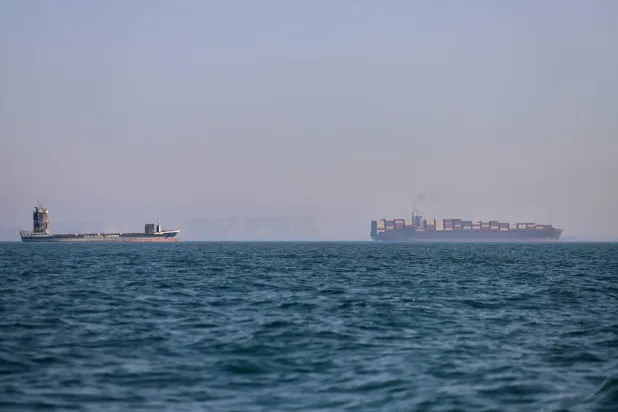 سفينة حاويات وأخرى للشحن في مضيق هرمز (أ.ب)