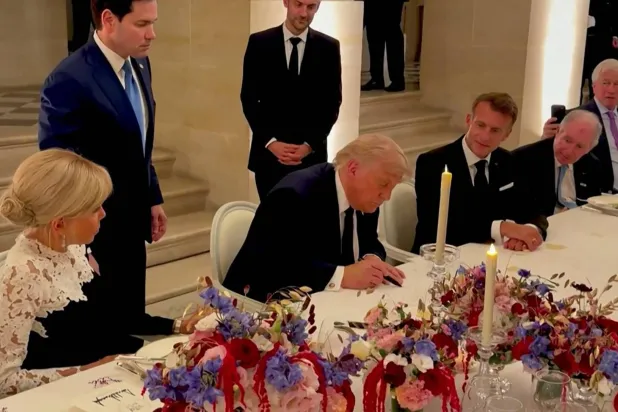 الرئيس الأميركي دونالد ترمب وهو يوقع على الاتفاق في فرنسا (أ.ف.ب)