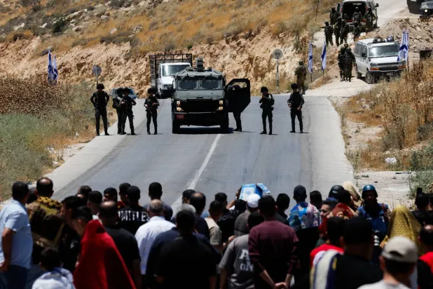 الجيش الإسرائيلي يغلق الطريق في حين يحتج فلسطينيون على الاستيطان قرب الخليل بالضفة الغربية المحتلة الجمعة (رويترز)
