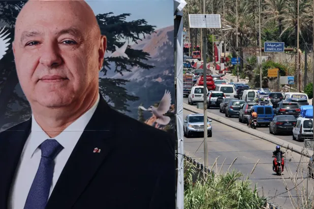 صورة عملاقة للرئيس اللبناني جوزيف عون مثبتة على المدخل الشمالي لمدينة صيدا وتظهر في الصورة سيارات النازحين من الجنوب باتجاه بيروت (إ.ب.أ)