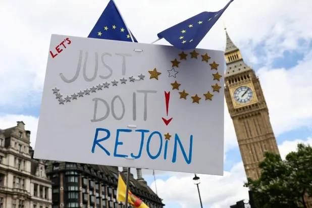 A placard is held as people walk past the Elizabeth Tower, commonly known as Big Ben, during the National Rejoin March IV organized by National Rejoin March (NRM), marking ten years since Britain voted to leave the European Union in 2016 and calling for closer cooperation between Britain and Europe, in London, Britain, June 20, 2026. (Reuters)