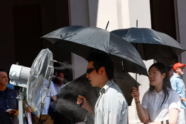  A man stands in front of a cooler spraying water ahead of Thom Browne’s Spring/Summer 2027 men’s collection show as part of Milan Fashion Week, in Milan, Italy, June 22, 2026. (Reuters)
