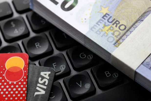 Euro banknotes, Visa and Mastercard cards are placed on a keyboard in this illustration taken September 24, 2025. (Reuters) 