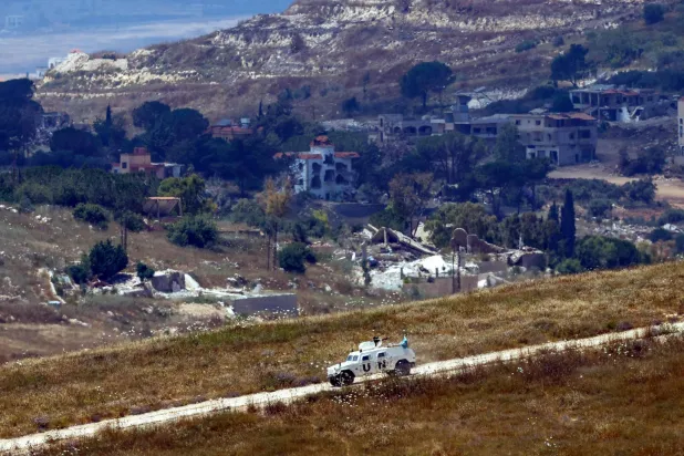 This picture taken from a position in northern Israel, near the border with Lebanon shows a United Nations Interim Force in Lebanon (UNIFIL) armored vehicle driving past destroyed buildings in southern Lebanon on June 22, 2026. (AFP)