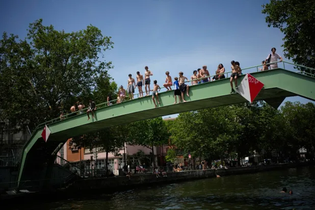Parisians bath in the Canal Saint-Martin in Paris, as the national weather service, Meteo France, placed 54 departments, about half the country, under a red heat wave alert, Tuesday, June 23, 2026. (AP Photo/Christophe Ena )