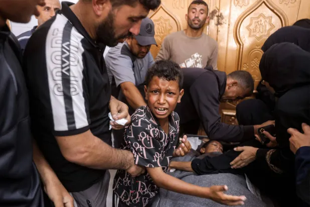 طفل فلسطيني ينتحب بجوار جثمان شقيقه الذي قتلته غارة إسرائيلية في خان يونس جنوب غزة يوم الأربعاء (أ.ف.ب)