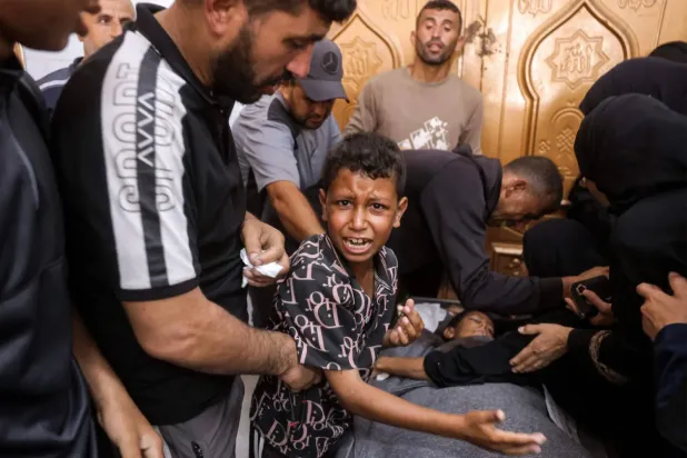 Filistinli bir çocuk, Gazze'nin güneyindeki Han Yunus'ta İsrail hava saldırısında öldürülen kardeşinin cesedinin yanında ağlıyor (Arşiv-AFP)