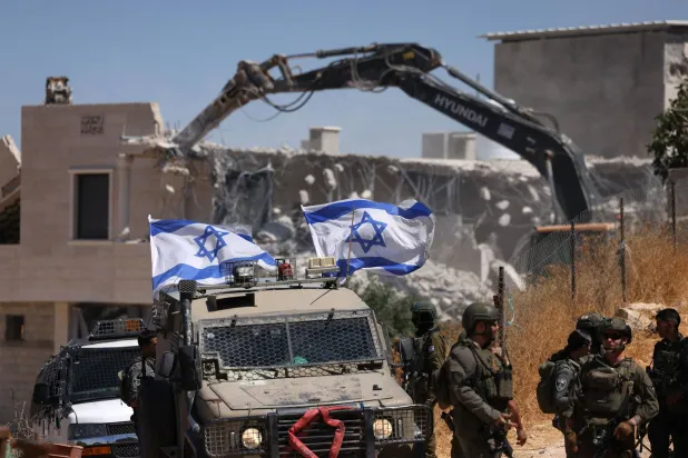Israeli bulldozers guarded by Israeli soldiers demolish the home belonging to the Palestinian al-Atrash family, citing the lack of a building permit, in the village of Qilqes, a few kilometers from the Israeli settlement of Beit Hagai, just south of the Israeli-occupied West Bank city of Hebron on June 23, 2026. (AFP)