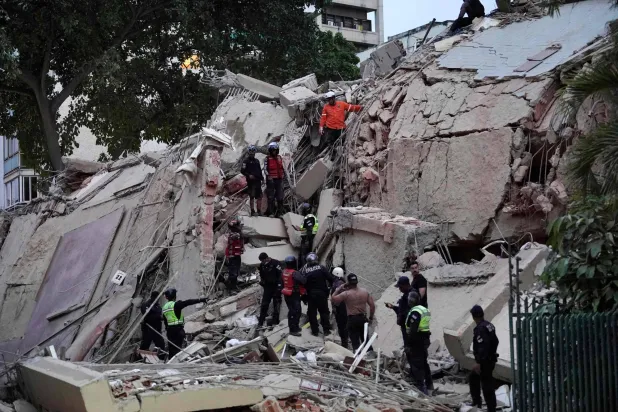 TOPSHOT - Rescuers search for victims in a collapsed building following an earthquake in Caracas on June 24, 2026. (Photo by Manaure Quintero / AFP)