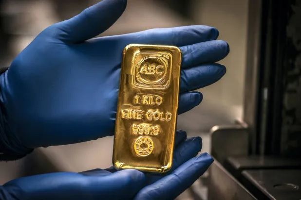 A worker displays gold bullion bar at the ABC Refinery in Sydney - AFP
