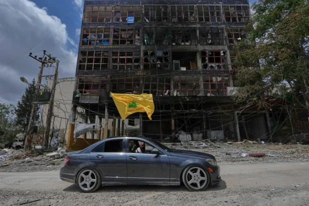 A man with a Hezbollah flag drives past a damaged building following a ceasefire between Israel and Hezbollah in the town of Nabatiyeh, southern Lebanon, Monday, June 22, 2026. (AP Photo/Mohammed Zaatari)