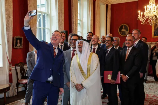 وزير التجارة البريطاني كريس براينت يلتقط صورة جماعية مع الأمين العام لمجلس التعاون الخليجي جاسم البديوي وأعضاء الوفد بعد التوصُّل إلى اتفاقية يوم 20 مايو (رويترز)