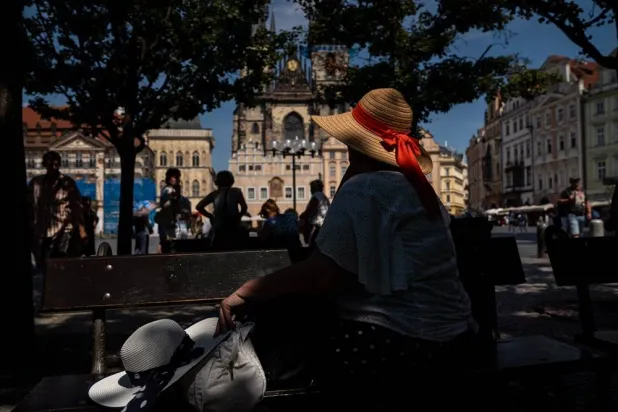 A woman sits in the shade during a hot, sunny day at Old Town Square in Prague, Czech Republic, 27 June 2026. (EPA)