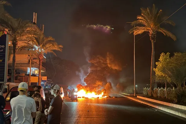  Hezbollah supporters block the old airport road in the southern suburbs of Beirut, with burning tires to protest against the trilateral agreement that was signed between the US, Lebanon and Israel on June 27, 2026. (AFP) 