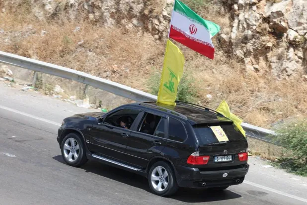  A car with Iranian and Hezbollah flags attached to it as displaced people make their way back to their homes in southern Lebanon following an interim deal between the US and Iran, in Sidon, Lebanon, June 24, 2026. (Reuters)