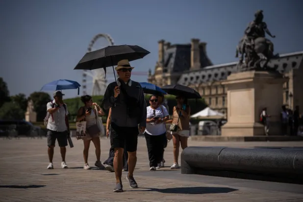 Tourists with umbrellas walk in Paris during a heat wave, Saturday, June 27, 2026. (AP Photo/Aurelien Morissard)
