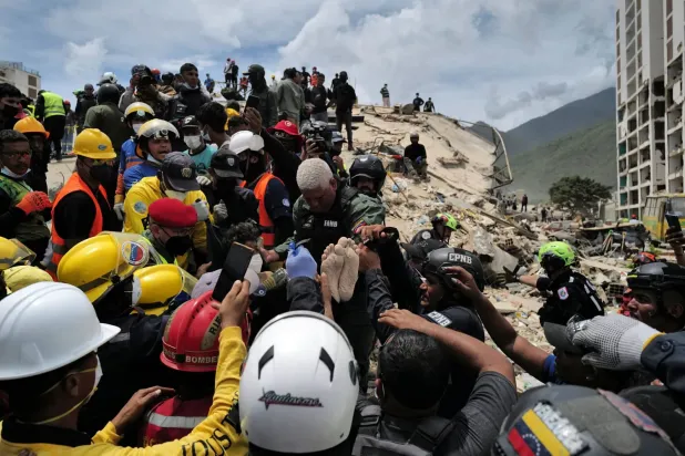Kurtarma ekipleri La Guaira'daki enkaz altından çıkarılan bir depremzedeyi taşıyor (AFP)