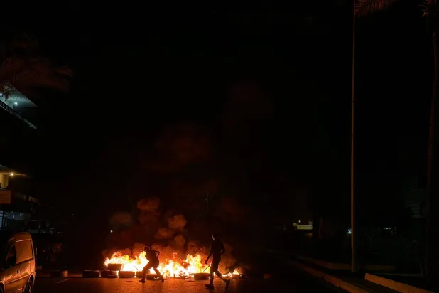 أنصار لـ«حزب الله» يقطعون طريق المطار القديمة في الضاحية الجنوبية لبيروت بإطارات مشتعلة السبت احتجاجاً على الاتفاق الثلاثي الموقع بين الولايات المتحدة وإسرائيل ولبنان 2026 (أ.ف.ب)