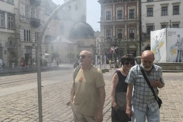 People cool themselves with water sprayed from a special sprayer set up on a sidewalk during a hot day in Lviv, Western Ukraine, 29 June 2026. (EPA)