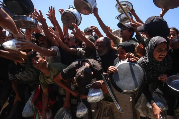 Displaced Palestinians gather to receive hot meals distributed by a charity kitchen in the Khan Younis refugee camp in the southern Gaza Strip on June 29, 2026. (AFP)