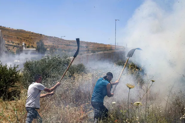 Men attempt to extinguish a fire in a field in the Palestinian town of Huwara in the occupied West Bank on June 6, 2026, after a reported arson attack by Israeli settlers according to local officials. (Photo by JAAFAR ASHTIYEH / AFP)