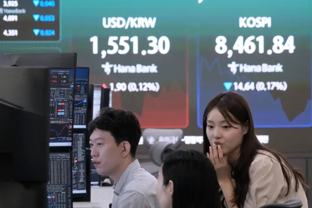 متداولون يعملون قرب شاشة تعرض مؤشر «كوسبي» وسعر صرف العملات الأجنبية بين الدولار والوون الكوري الجنوبي في بنك هانا بسيول (أ.ب)