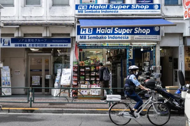 A police officer bikes past a convenience store in the Okubo–Shin area in Tokyo, a neighborhood known for its large immigrant communities. Andrew CABALLERO-REYNOLDS / AFP
