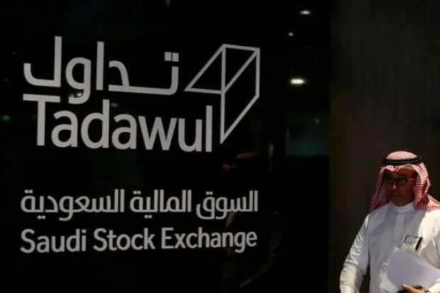 رجل يسير أمام لافتة «تداول» (أ.ف.ب)