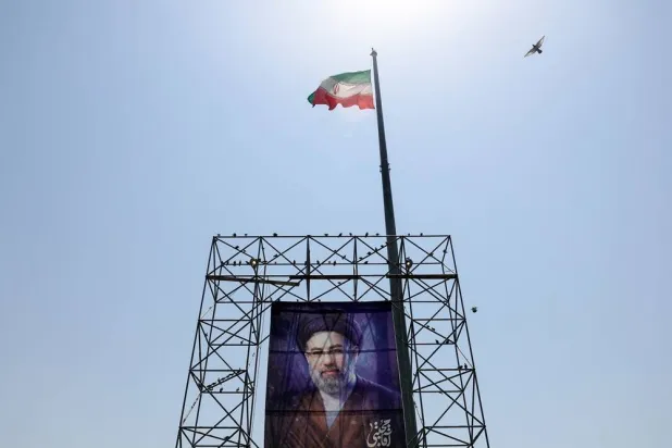 A bird flies near an Iranian flag and a banner with a picture of Iran's Supreme Leader Mojtaba Khamenei, in Tehran, Iran, June 28, 2026. Majid Asgaripour/WANA (West Asia News Agency) via Reuters