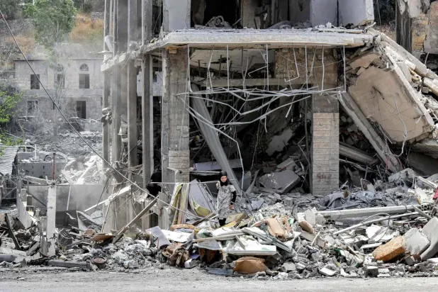 Lübnan'ın güneyindeki Nebatiye el-Fevka beldesinde, yıkılmış bir binanın enkazını inceleyen bir kadın (AFP)