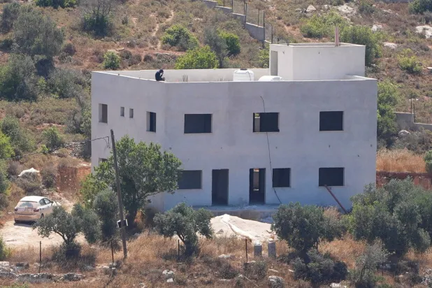  An Israeli settler sits on the roof of the Palestinian Salameh family house, which was taken over by Israeli settlers in the village of Jalud in the Israeli-occupied West Bank July 2, 2026. (Reuters)