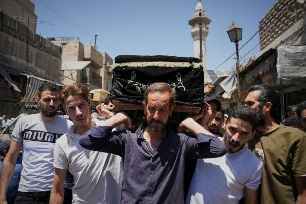 Mourners carry the coffin of Fathi Muhammad Saeed Qabbani, who was killed Tuesday when an explosive device detonated in a cafe near Damascus' main courthouse complex, during his funeral in the Al-Midan neighborhood of Damascus, Syria, Friday, July 3, 2026. (AP Photo/Omar Albam)