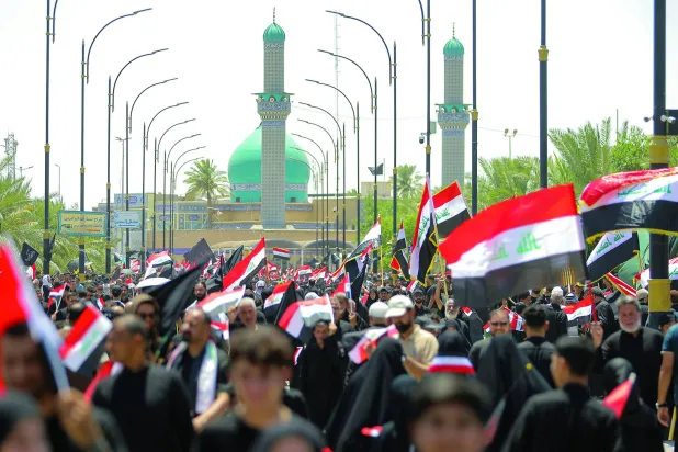 أنصار مقتدى الصدر يلوّحون بالعلم العراقي خلال مظاهرة دعماً لإجراءات الحكومة العراقية لمكافحة الفساد في النجف (أ.ب)