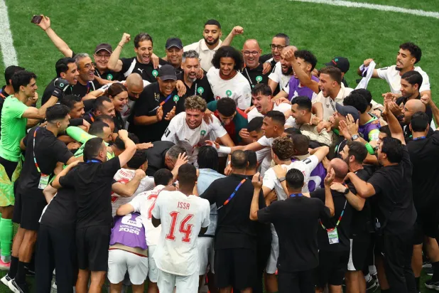 لاعبو المغرب يحتفلون بعد التأهل إلى ربع النهائي (رويترز)
