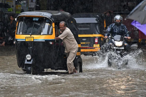 04 July 2026, India, Mumbai: A driver pushes his auto rickshaw (L) on a flooded street after a heavy rain in Mumbai. Photo: Ashish Vaishnav/SOPA Images via ZUMA Press Wire/dpa