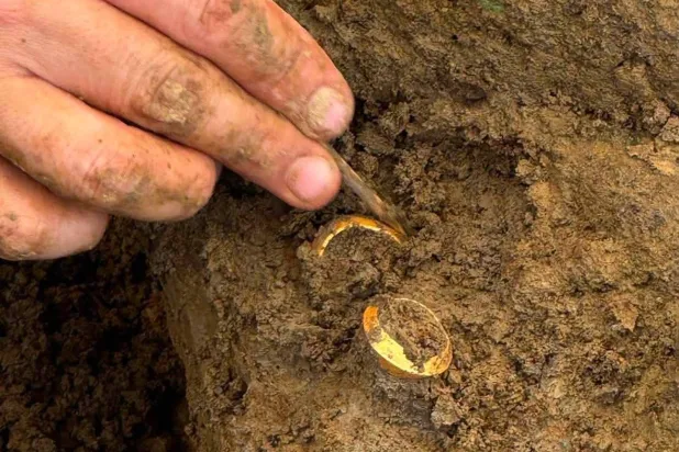 In this photo released by The Fine Arts Department, an archaeologist shows two rings with human bones during an ongoing dig at the Don Yai Thong archeological site in Phetchaburi province, Thailand Thursday, July 2, 2026. (The Fine Arts Department via AP)