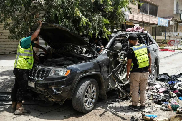 مسعفون وعناصر إنقاذ يعاينون السيارة التي استهدفت بغارة إسرائيلية في النبطية بجنوب لبنان وأدت إلى مقتل 4 أشخاص (أ.ف.ب)