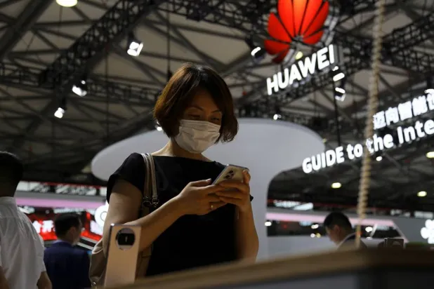 A visitor checks a mobile phone near the Huawei logo during the Mobile World Congress in Shanghai, China June 28, 2023. (Reuters)