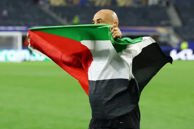 حسام حسن يرفع العلم الفلسطيني بعد فوز مصر على أستراليا والتأهل للدور 16 في كأس العالم لكرة القدم (رويترز)