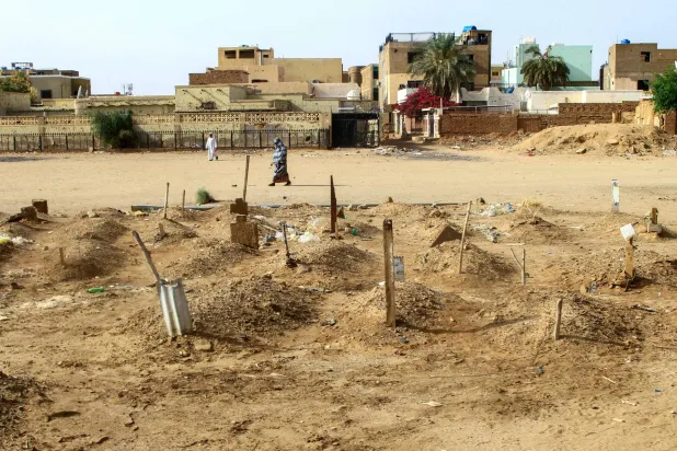 امرأة سودانية تسير بين مدافن سودانيين في أم درمان قتلوا في الحرب (أ.ف.ب) 