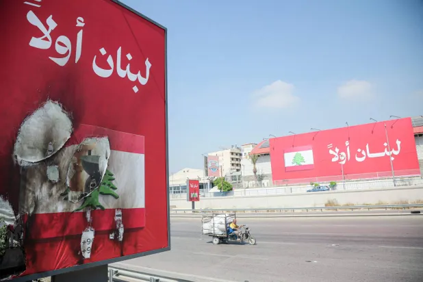 Vehicles drive past billboards that read in Arabic, "Lebanon first". (Photo by ibrahim AMRO / AFP) / 