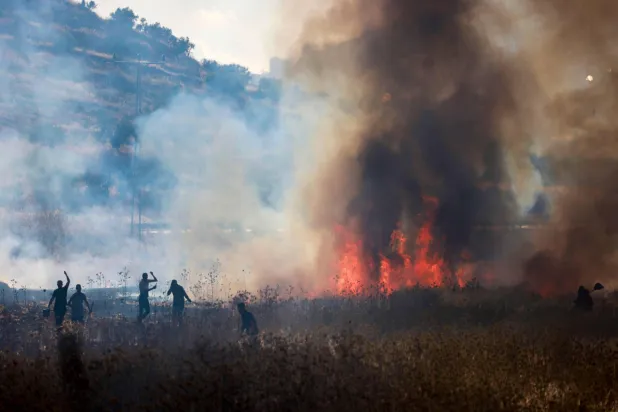 فلسطينيون يحاولون إخماد حريق أشعله مستوطنون في حقول قمح بقرية سالم شرق نابلس في الضفة الغربية المحتلة يوم الجمعة (أ.ف.ب)