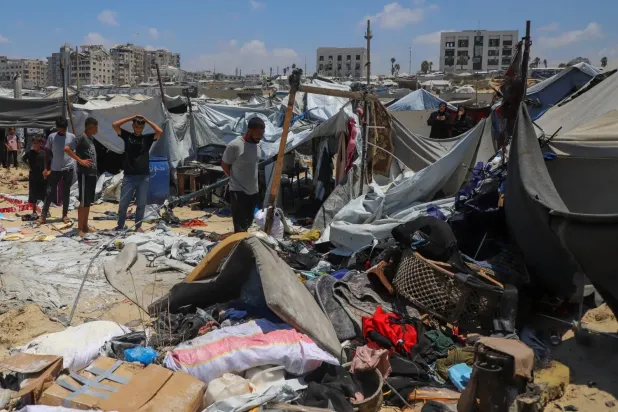 İsrail’in Gazze şehrinde yerinden edilmişlerin kaldığı bir çadır kampını hedef alan hava saldırısının ardından bölgeyi inceleyen Filistinliler (Reuters)