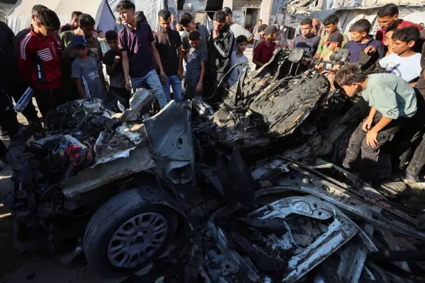 Filistinliler, İsrail'in Gazze kentinde bir aracı hedef aldığı hava saldırısının ardından olay yerini inceledi. (Reuters)