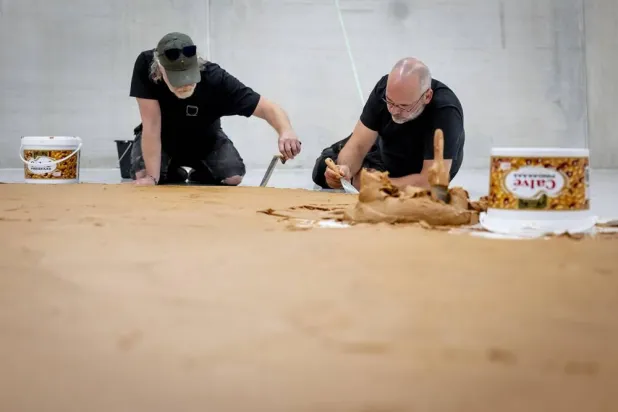"Peanut Butter Plasterers" are spreading a floor of peanut butter, without chunks, in the Depot of Museum Boijmans Van Beuningen, in Rotterdam, Netherlands, 03 July 2026, as a tribute to the late artist and TV producer Wim T. Schippers. (EPA)