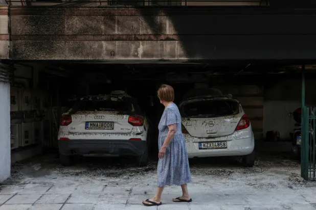 FILE PHOTO: A woman walks past damaged cars and a building after attackers firebombed three residential buildings linked to Greece's governing party in the northern city of Thessaloniki, Greece, July 1, 2026. REUTERS/Alexandros Avramidis/File Photo