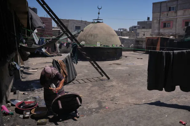فلسطينية تنظف طاولة على سطح مسجد تحول ملجأً لنازحين في خان يونس جنوب قطاع غزة الجمعة (أ.ب)
