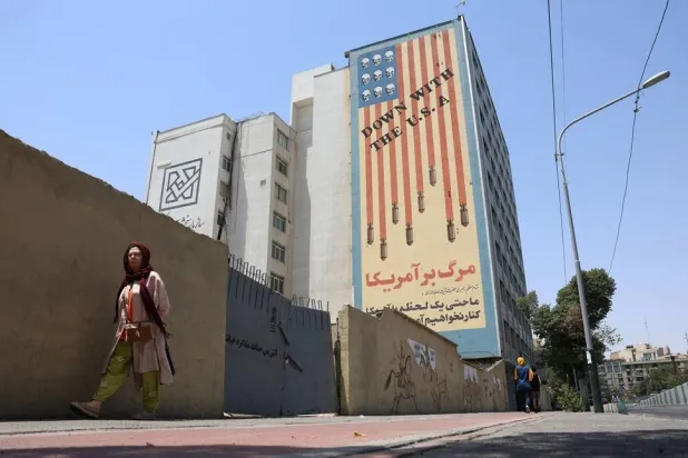 An Iranian woman walks near an anti-US mural in a street in Tehran, Iran, 09 July 2026. (EPA)